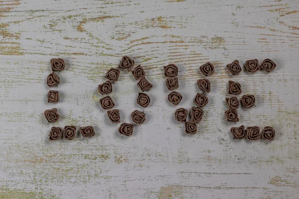 Ahşap arka plan, üstten görünüm üzerinde kahverengi gül koyu kahverengi aşk mektupları. Metin aşk merkezinde ahşap arka plan üzerinde. Tatil sevgili için tebrikler.