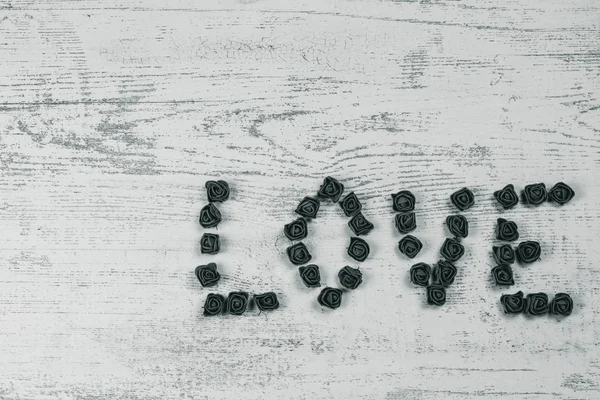 Ahşap arka plan, üstten görünüm üzerinde kahverengi gül karanlık aşk mektupları. Kağıt ahşap arka plan üzerinde kırmızı küçük kalpler. Tatil sevgili için tebrikler.