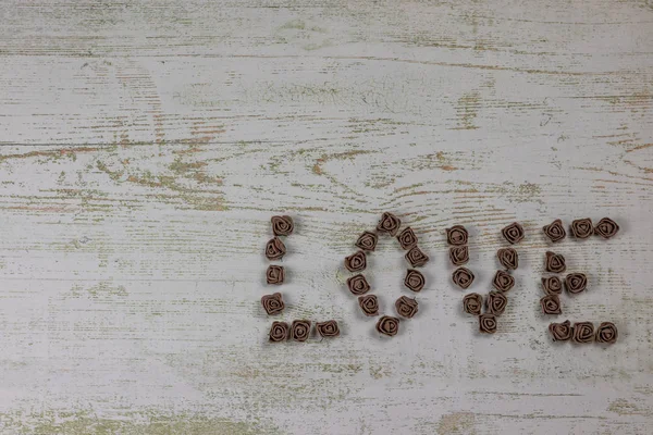 Ahşap arka plan, üstten görünüm üzerinde kahverengi gül koyu kahverengi aşk mektupları. Ahşap arka plan üzerinde metin aşk. Tatil sevgili için tebrikler.