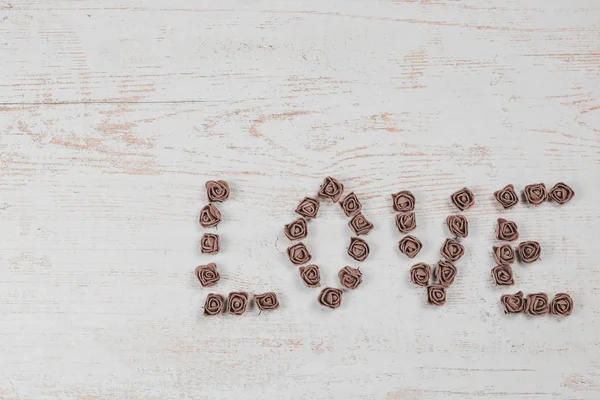 Ahşap arka plan, üstten görünüm üzerinde kahverengi gül koyu kahverengi aşk mektupları. Ahşap arka plan üzerinde metin aşk. Tatil sevgili için tebrikler.