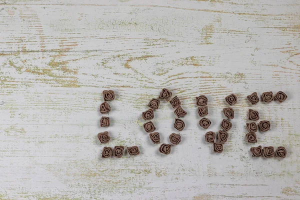 Ahşap arka plan, üstten görünüm üzerinde kahverengi gül koyu kahverengi aşk mektupları. Ahşap arka plan üzerinde metin aşk. Tatil sevgili için tebrikler.