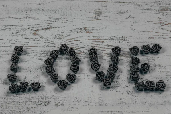 Gül ahşap arka plan, bokeh yan görünüm üzerinde koyu kahverengi aşk mektupları. Metin aşk merkezinde ahşap arka plan üzerinde. Tatil sevgili için tebrikler.