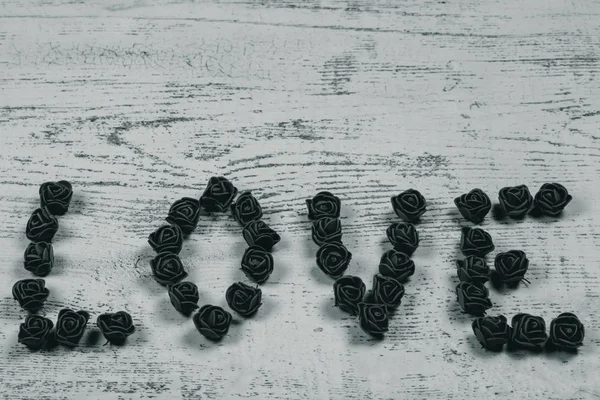 Gül ahşap arka plan, bokeh yan görünüm üzerinde koyu kahverengi aşk mektupları. Metin aşk merkezinde ahşap arka plan üzerinde. Tatil sevgili için tebrikler.