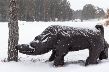Ahşap domuzu kışın çam gnaws. Ormanda kar yağışı domuz bir ahşap heykel.