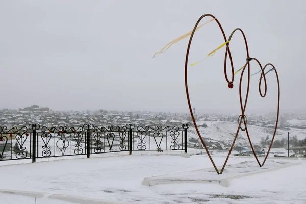 Red hearts from iron pipes in winter. In the wind in the winter of red heart pipes with locks. Iron fence with locks.