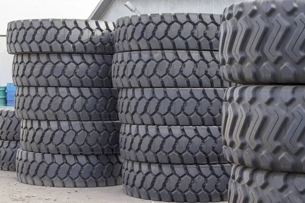 Grands pneus en caoutchouc pour camions couchés dans la rue. De nombreux pneus en gros plan avec une grande bande de roulement sont couchés sur le sol . — Photo