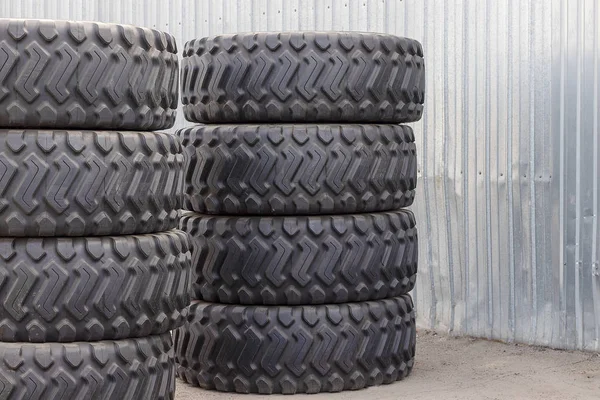 Pneus de borracha grandes para caminhões deitados na rua. Muitos pneus novos close-up com uma grande banda de rodagem estão no chão . — Fotografia de Stock