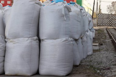 Büyük beyaz tuz torbaları sokakta yatıyor. Endüstriyel gübreler torbalarda bir yığın halinde saklanır.