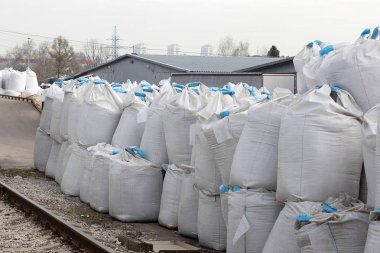 Büyük beyaz tuz torbaları sokakta yatıyor. Endüstriyel gübreler torbalarda bir yığın halinde saklanır.