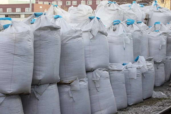 Tuz içinde mavi kurdele ile büyük beyaz çanta sokakta yalan. Endüstriyel gübreler torbalarda bir yığın halinde saklanır.