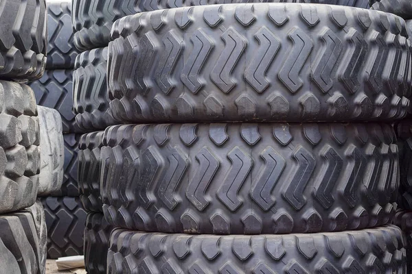 Velké gumové pneumatiky pro náklaďáky ležící na ulici. Černé pneumatiky se blíží k velkému schodu na zemi. — Stock fotografie
