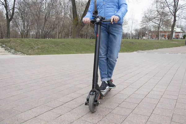 Het meisje rijdt op een elektrische scooter in het Park op de weg met een actie camera. Technologisch milieuvriendelijk transport. Moderne actieve stedelijke levensstijl. — Stockfoto