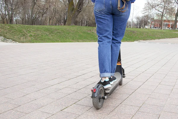 Chica montando un scooter eléctrico en el parque en la pista. Transporte tecnológico respetuoso con el medio ambiente. Estilo de vida activo moderno . —  Fotos de Stock