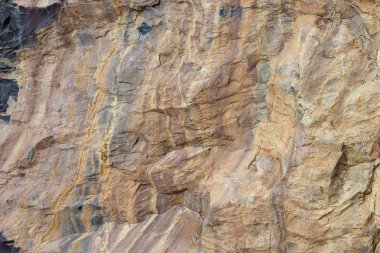 Doğal taş kabartma, kırmızı renk. Küçük çatlaklar ile kahverengi bir doku ile arka plan kaya. Farklı renklerde yıpranmış taş katmanları.