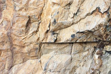 Doğal taş kabartma, kırmızı renk. Küçük çatlaklar ile gri bir doku ile arka plan kaya. Farklı renklerde yıpranmış taş katmanları.