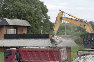 Ekskavatör inşaat atıklarını kırmızı bir kamyona yükler. Ekskavatör kovası inşaat atıkları, beton bir kamyonun arkasına döker. Tahrip beton, inşaat atıkları. Karayolu.