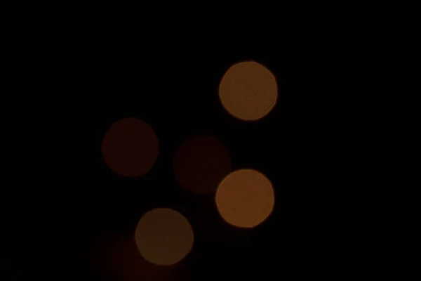 Färgade fläckar av ljus på en svart bakgrund närbild. Svart bakgrund med en glödlampa suddig röd, gul och orange fläck. Inget fokus. — Stockfoto
