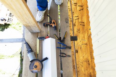 İnşaat araçları açı değirmeni, açı ölçüm cetveli, pliers, demir makas, matkap, bant ölçüsü. Ahşap iskele üzerinde sokakta inşaat bir çalışma aracı yatıyor.