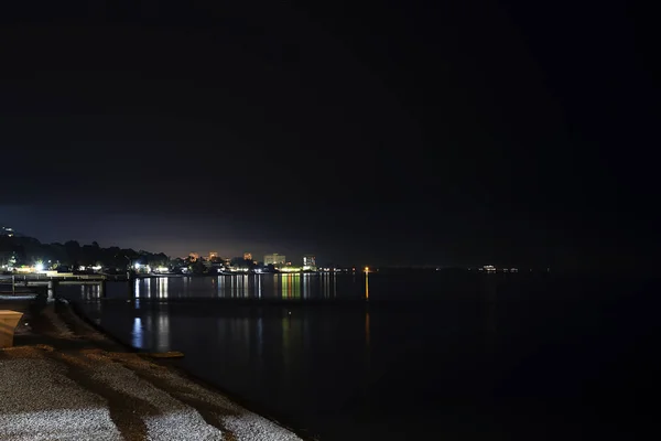 Νυχτερινή πόλη δίπλα στη θάλασσα. Τα φωτεινά φώτα της πόλης ταξιδεύουν, ο τουρισμός. Νυχτερινή παραλία της άμμου και βότσαλα, Αμπχαζία Gagra. — Φωτογραφία Αρχείου