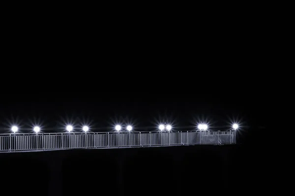 Белый ночной мост со светом. Лучи белого света от фонарей, черная ночь. Мост висит в воздухе . — стоковое фото