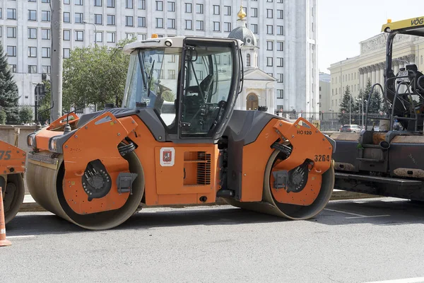 Rusya, Moskova, 2019-08-10. Turuncu bir yol silindiri yolun yanında duruyor. Karayolunun onarımı için hazırlık. Teknik Avtodor.