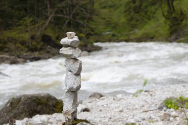 Cairn, taş heykel, dağ nehri suyuna karşı. Zen, uyum, denge simgeleyen ormanda piramidin beyaz taşlar.
