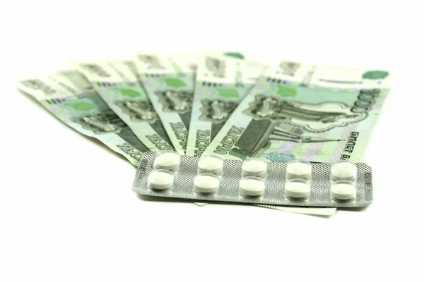 Banknoty pieniędzy 1000 rubli z białymi pigułek medycznych na białym tle. Pieniądze na leki dla osób starszych. — Zdjęcie stockowe