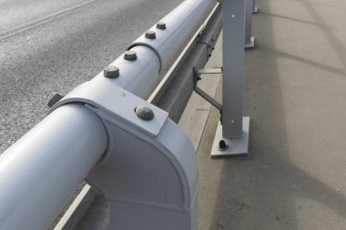 Çelik cıvataile birbirine bağlanmış borulardan yapılmış sokak yolu çiti. Yaya güvenliği için yuvarlak gri borular. Cıvata bağlantısı.