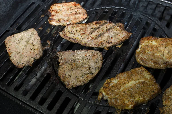 Μαριναρισμένο χοιρινό με μπαχαρικά είναι ψητό σε μια σχάρα σιδήρου αέριο. Πολλά ζουμερά κομμάτια κρέατος είναι μαγειρεμένα σε μπάρμπεκιου. — Φωτογραφία Αρχείου
