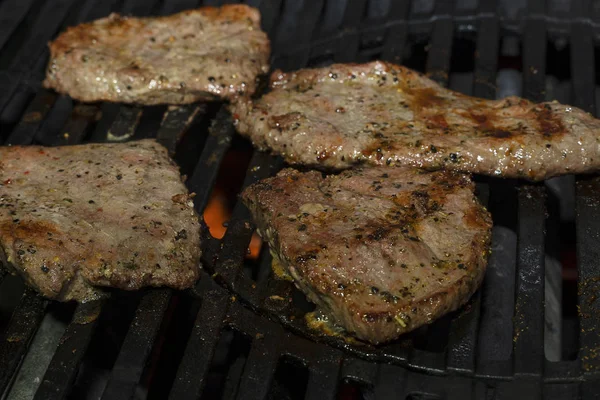 Marynowane mięso wieprzowe jest grillowane na Żelaznym grillu gazowym. Soczyste duże kawałki mięsa wołowego są gotowane na grilla. — Zdjęcie stockowe