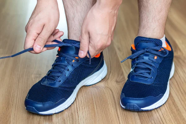 Guy athlete in cross-country running shoes tie laces.