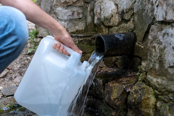 Man pours water in a mountain spring.
