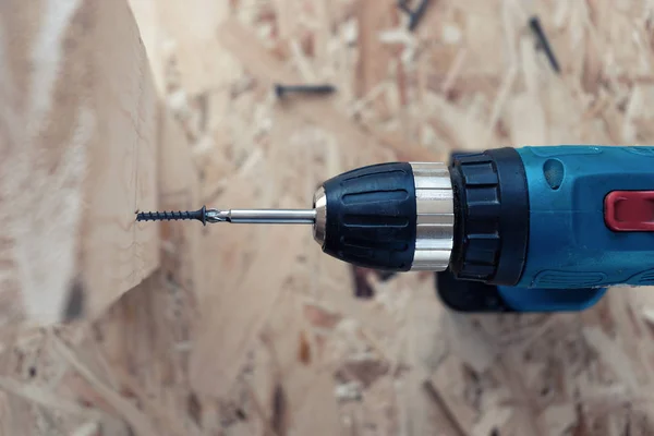 Cordless drill twists the screw into the wood