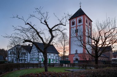 Gündoğumunda kilise ve eski binaları olan Odenthal köyünün merkezi, Bergisches Toprakları, Almanya
