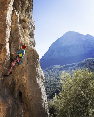 kadın dağcı. kaya tırmanışçısı kayalık bir duvara tırmanıyor. kadın sert hareket yapar.