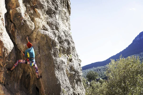 kadın dağcı. kaya tırmanışçısı kayalık bir duvara tırmanıyor. kadın sert hareket yapar.