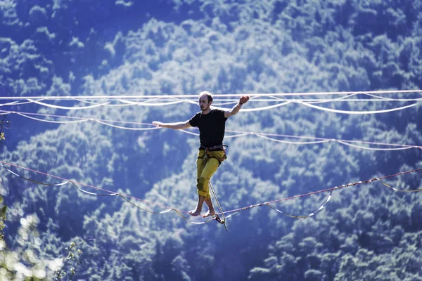 高耸在绳子上 高耸在高山的背景上 大自然的极端运动 在吊带上保持平衡 在高度上保持平衡 — 图库照片