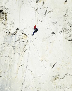Genç adam uçurumun üzerinde zorlu rota tırmanma sırasında ararken.