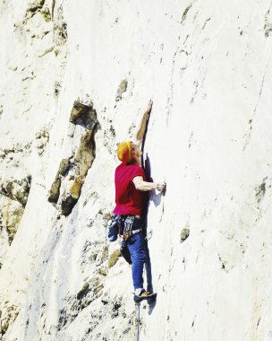 Genç adam uçurumun üzerinde zorlu rota tırmanma sırasında ararken.