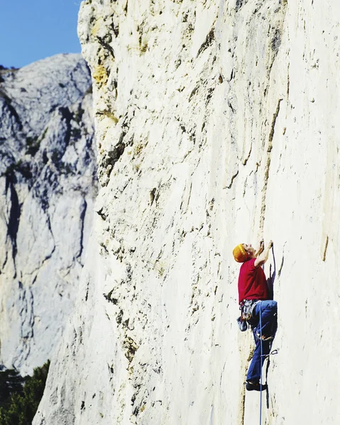崖の上のチャレンジングなルートを登りながら見上げる若い男 — ストック写真