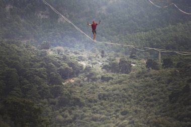 Highliner ipte. Dağların arka planında yüksek bir çizgi. Doğada ekstrem bir spor. Askıda dengede duruyor. İrtifada denge.