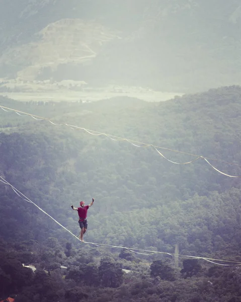 高耸在绳子上 高耸在高山的背景上 大自然的极端运动 在吊带上保持平衡 在高度上保持平衡 — 图库照片