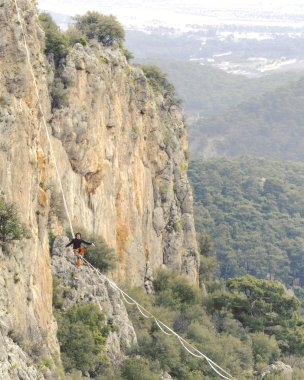 Highliner ipte. Dağların arka planında yüksek bir çizgi. Doğada ekstrem bir spor. Askıda dengede duruyor. İrtifada denge.