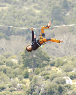 Highliner ipte. Dağların arka planında yüksek bir çizgi. Doğada ekstrem bir spor. Askıda dengede duruyor. İrtifada denge.