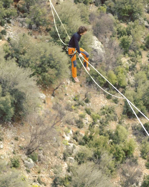 Highliner ipte. Dağların arka planında yüksek bir çizgi. Doğada ekstrem bir spor. Askıda dengede duruyor. İrtifada denge.