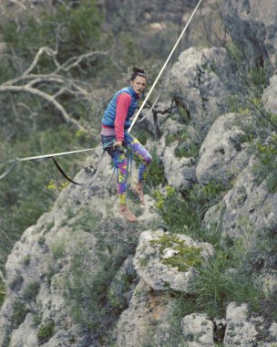 Highliner ipte. Dağların arka planında yüksek bir çizgi. Doğada ekstrem bir spor. Askıda dengede duruyor. İrtifada denge.