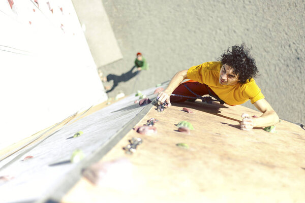 Man bouldering at an indoor climbing centre. Climber practicing rock climbing at an indoor climbing gym.