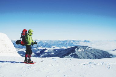 Bir sırt çantası içinde kar ayakkabıları ile dağlarda hiking kış.