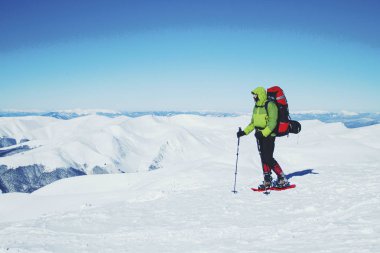 Bir sırt çantası içinde kar ayakkabıları ile dağlarda hiking kış.