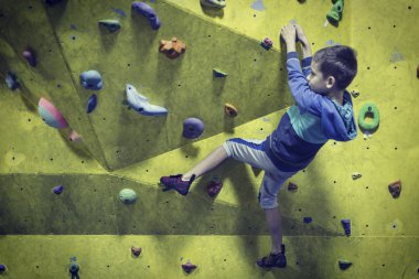 Küçük çocuk kapalı bir kaya duvarı tırmanma. Spor hayatı kavramı.